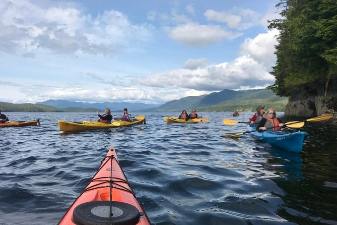 Kayakers paddling a calm channel under a wide sky