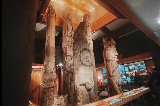 Weathered totem poles standing indoors under soft gallery lighting